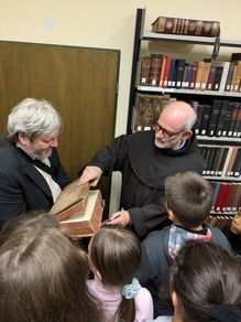 Ein Buch aufschlagen: Schulleiter Stefan Weidner und die Relikinder bekommen von Bruder Michael in der Klosterbibliothek gezeigt, wie alte Bücher „aufgeschlagen“ wurden